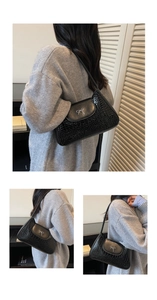 Close-up of black crocodile pattern faux leather shoulder bag with silver bow detail