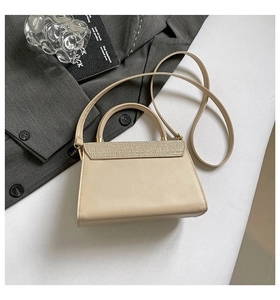 Detailed view of beige faux leather handbag with shimmering sequined flap on office suit