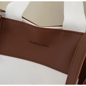 Detailed view of canvas and brown leather stitching with Fashion & Bag embossed logo