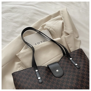 Close-up of brown monogram tote bag with metal snap closure and leather straps