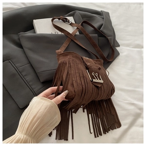 Close-up of brown suede crossbody bag with long fringe tassels and silver buckle detail