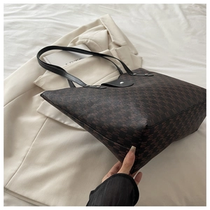 Detail of a deep brown monogram tote bag with black leather flap and silver snap button