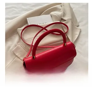 Détail du sac à main en cuir rouge avec poignée ergonomique et finitions dorées