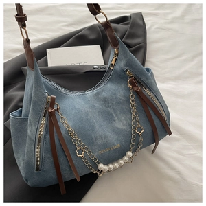 Close-up of blue denim shoulder bag with pearl chain and leather strap detail