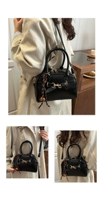 Detail of black Boston style shoulder bag with gold horsebit hardware and woven charm