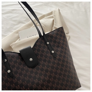 Detail of large brown monogram tote bag with black leather straps and silver metal studs
