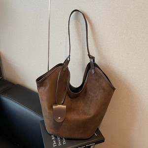 Sac cabas vintage en cuir mat marron foncé avec fines anses sur fond de livre design