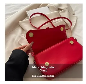 Détail du sac à bandoulière rouge vif avec son fermoir magnétique doré et finitions chic