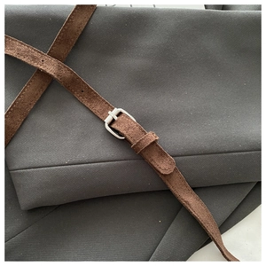 Detailed macro view of dark grey twill fabric with brown suede belt and silver square buckle