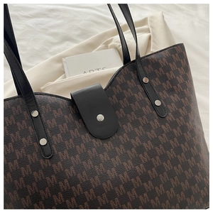 Close-up of vintage M-pattern tote bag showing leather strap and silver rivet details