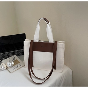 Detail of canvas tote bag with brown leather trim, laptop and headphones for work