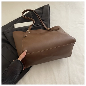 Détail du logo gaufré sur un grand sac cabas vintage en cuir marron pour le bureau