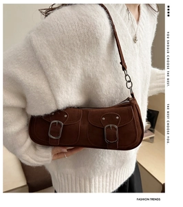 Close-up of brown suede bag with double buckle pockets and chain leather strap detail