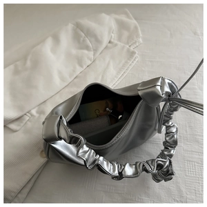 Close-up of silver metallic pleated handle handbag with glossy mirror finish
