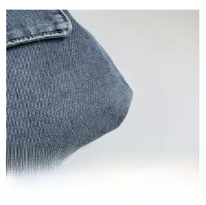 Detailed close-up of blue denim fabric with visible diagonal twill texture and stitching