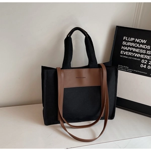 Detail of black canvas tote bag showing brown leather handles and fashion bag print