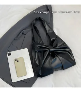 Détail du cabas en cuir PU noir à gros nœud, montrant la comparaison de taille avec l'iPad