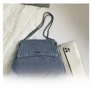 Detail view of a blue denim chain bag with a metal logo plate and spacious interior storage