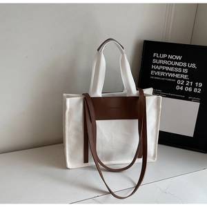 Detail of large canvas tote bag with brown leather accents and fashion engraving