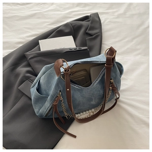 Detail of blue denim tote bag interior holding a wallet and phone with pearl chain