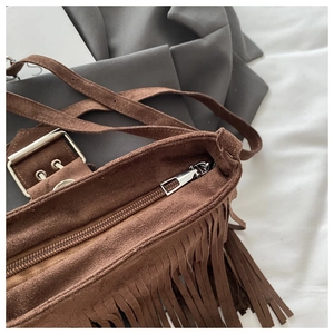 Macro shot of silver zipper and refined stitching on a brown suede tassel shoulder bag