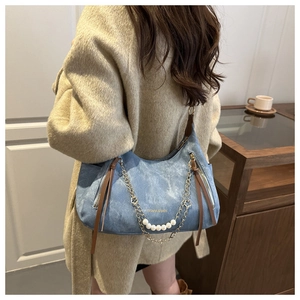 Detail view of retro denim shoulder bag featuring golden chain and white pearl charms