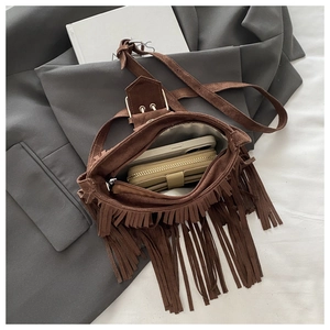 Detail showing the spacious interior of a brown suede tassel crossbody bag with daily items