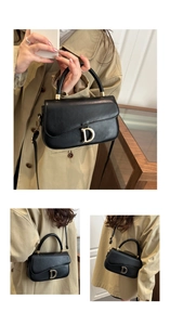 Détail d'un sac noir avec boucle dorée en D et poignée arrondie élégante pour femme