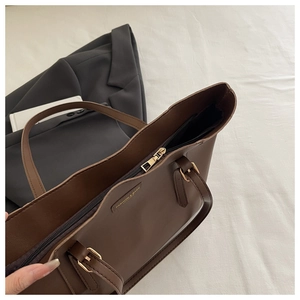 Gros plan détaillé d'un sac cabas en cuir marron foncé avec fermeture éclair et plaque dorée