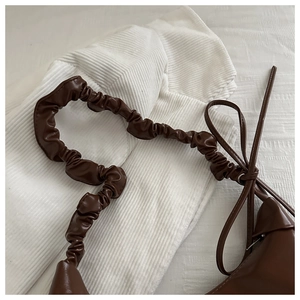 Detail of soft pleated brown PU leather shoulder strap with a decorative side bow knot