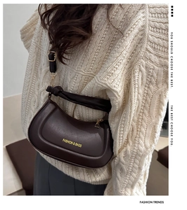 Close-up of brown semi-circle crossbody bag with Fashion & Bags text on beige sweater