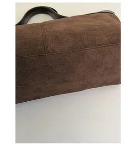 Close-up of reinforced bottom and fine stitching on dark brown matte suede tote bag