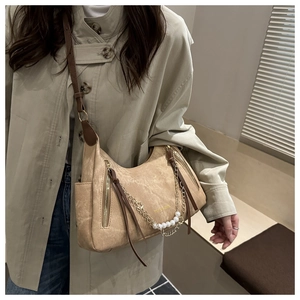 Close-up of khaki suede tote bag featuring pearl chain details and long tassels
