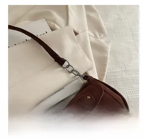 Detail of brown suede shoulder bag with vintage metal buckle and fine stitching