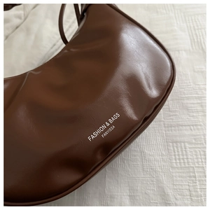 Close-up of dark brown crescent bag showing fine PU leather texture and Fanyissa logo