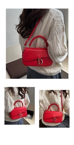 Détail du sac selle rouge avec pendentif D en métal doré et poignée en cuir lisse