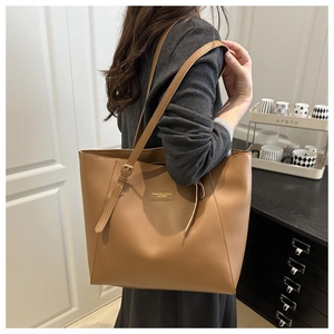 Détail du cabas marron caramel avec bandoulière réglable et plaque logo en métal chic