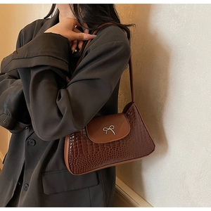 Detail of vintage brown croc-pattern leather shoulder bag with silver bow buckle