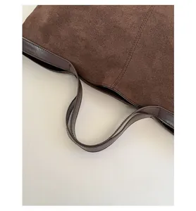 Detail of reinforced handles on a vintage dark brown suede tote bag with neat stitching
