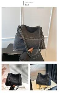 Detail of washed black denim crossbody bag with chain strap and metal flap bar decoration