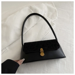Detail of black faux leather handbag featuring a leopard print flap and golden metal clasp