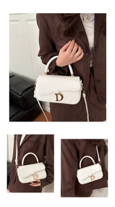 Détail du sac selle blanc avec boucle en D dorée et texture en cuir élégant