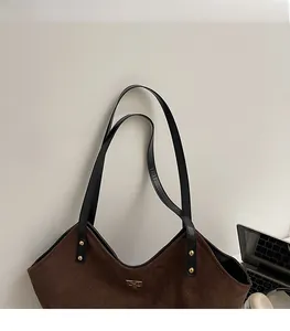 Close-up of brown suede tote bag with diamond stitching and golden metal logo detail
