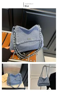 Blue washed denim messenger bag with metal chain strap and minimalist silver buckle detail