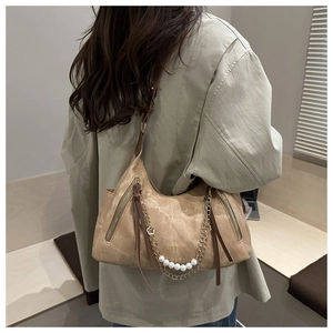 Close-up of khaki suede tote bag featuring decorative gold chains and white pearls
