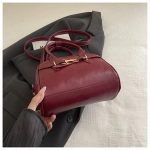 Close-up of wine red retro handbag with fine stitching and gold metallic buckle detail