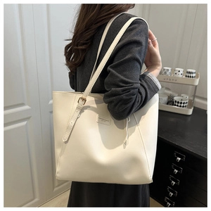 Détail d'un cabas blanc crème avec bandoulière réglable et écusson en cuir de mode