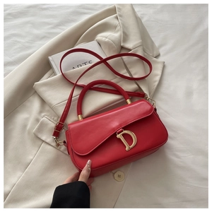 Détail d'un sac à main rouge en cuir avec boucle dorée en D et bandoulière amovible