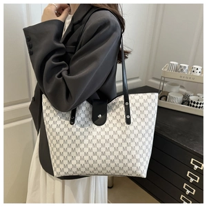 Detail of white tote bag with gray M-pattern and black leather strap for commuting