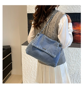 Detail of blue denim tote bag with silver leather-interwoven chain strap and flap closure